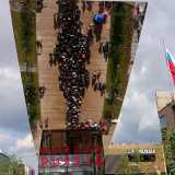 Uno specchio sopraelevato riflette il fiume di persone all'entrata del padiglione della Russia 